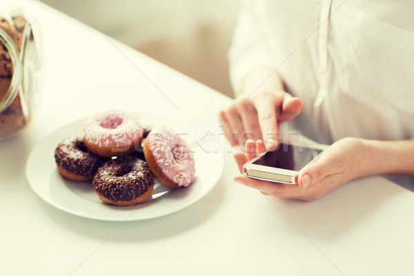 close up of hands with smart phone and donuts Stock photo © dolgachov