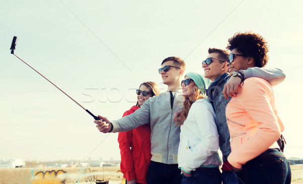 friends taking selfie with smartphone on stick Stock photo © dolgachov