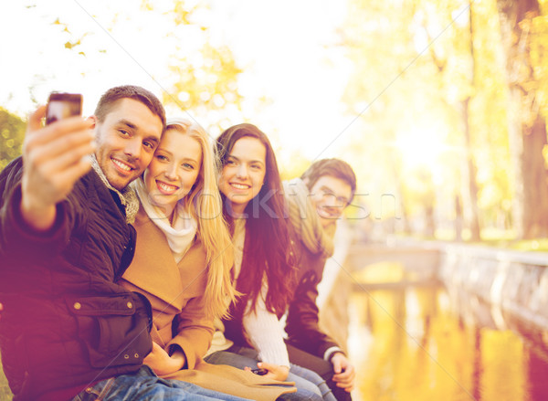 group of friends with photo camera in autumn park Stock photo © dolgachov