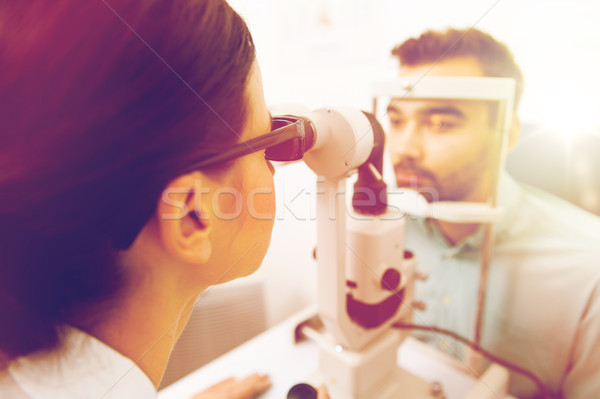 optician with slit lamp and patient at eye clinic Stock photo © dolgachov