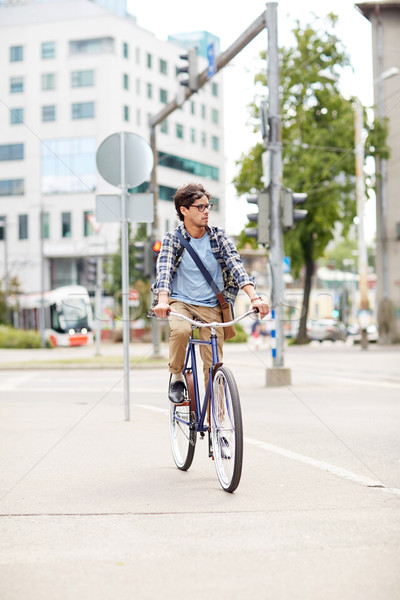 young hipster man with bag riding fixed gear bike Stock photo © dolgachov