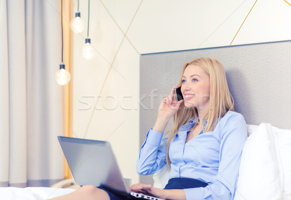 Stock photo: happy businesswoman with smartphone in hotel room