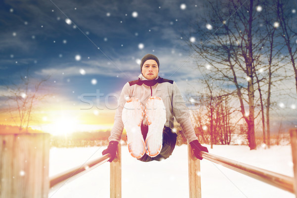 young man exercising on parallel bars in winter Stock photo © dolgachov