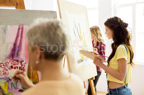 woman with easel painting at art school studio Stock photo © dolgachov