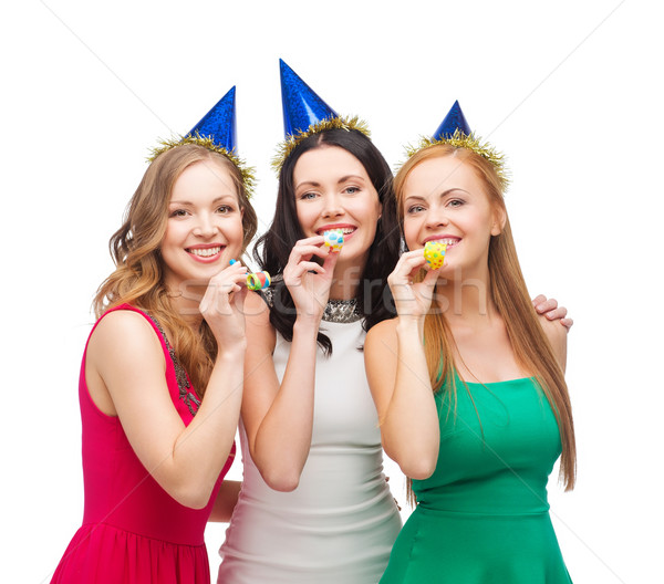 three smiling women in hats blowing favor horns Stock photo © dolgachov