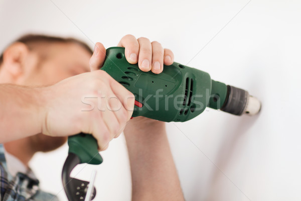 man with electric drill making hole in wall Stock photo © dolgachov