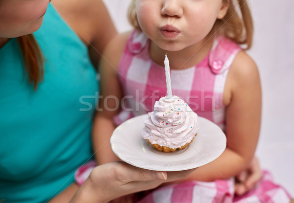 happy mother and girl blowing out cupcake candle Stock photo © dolgachov