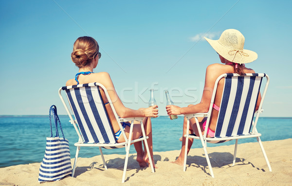 happy women sunbathing in lounges on beach Stock photo © dolgachov