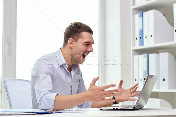 angry businessman with laptop and papers in office Stock photo © dolgachov