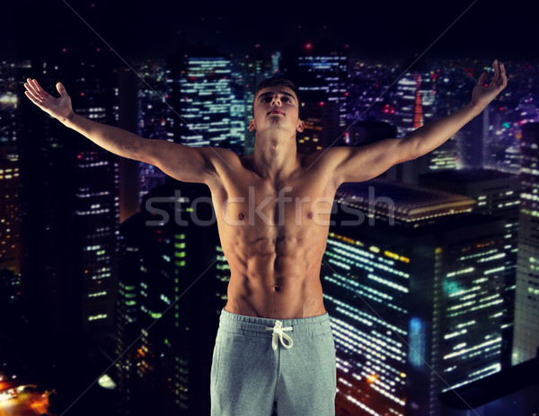 young male bodybuilder with raised hands Stock photo © dolgachov