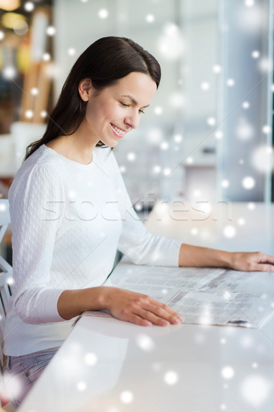 Stock photo: smiling young woman reading newspaper at cafe
