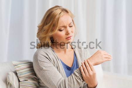 unhappy woman suffering from pain in hand at home Stock photo © dolgachov