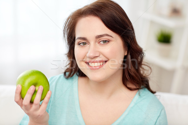 happy plus size woman eating green apple at home Stock photo © dolgachov