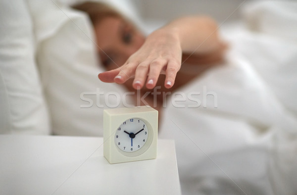 close up of woman with alarm clock in bed at home Stock photo © dolgachov