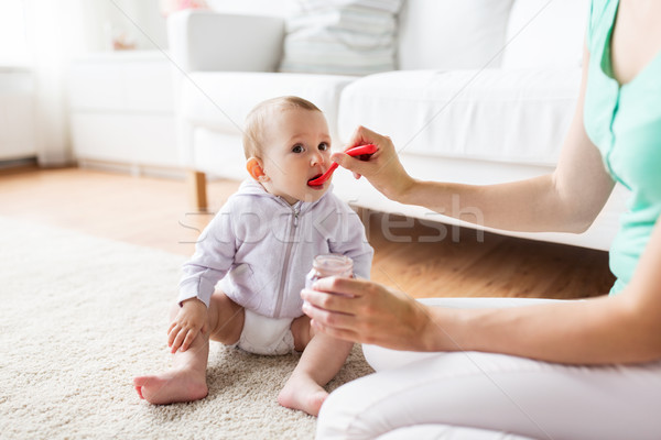 mother with spoon feeding little baby at home Stock photo © dolgachov