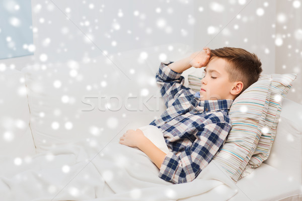 ill boy lying in bed and suffering from headache Stock photo © dolgachov