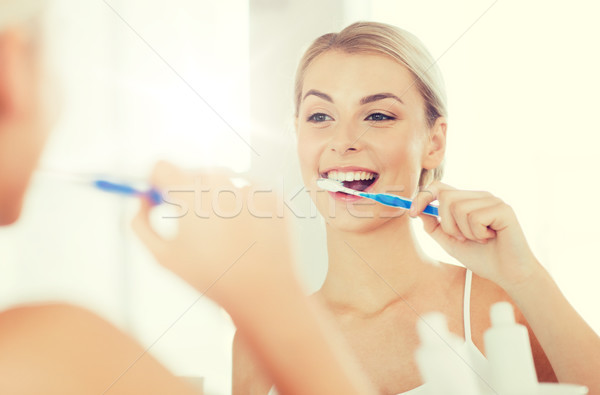 woman with toothbrush cleaning teeth at bathroom Stock photo © dolgachov