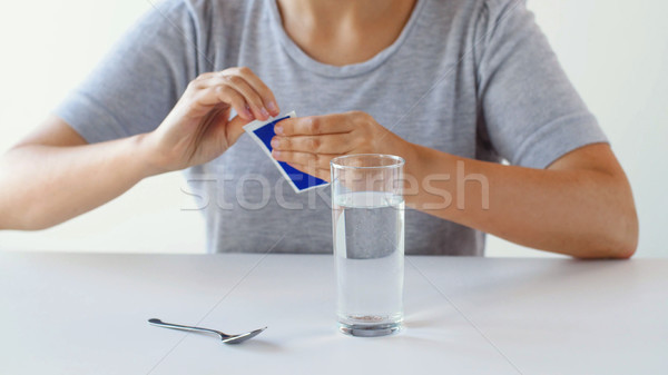 woman with glass of water opening pack of medicine Stock photo © dolgachov