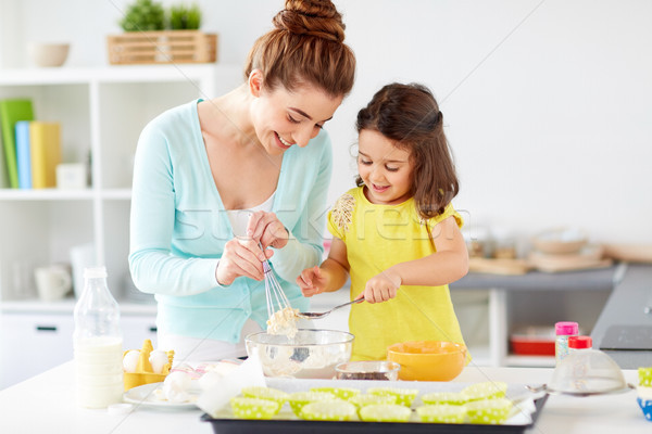 Stock photo: happy mother and daughter baking muffins at home