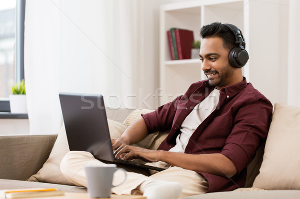 man in headphones with laptop listening to music Stock photo © dolgachov