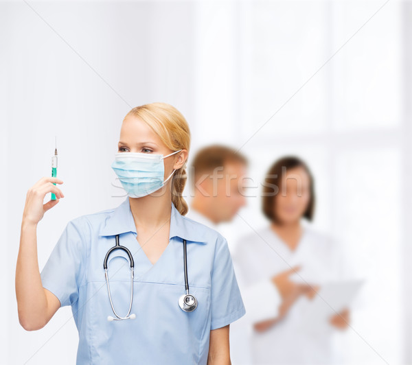 Női orvos nővér maszk tart injekciós tű Stock fotó © dolgachov