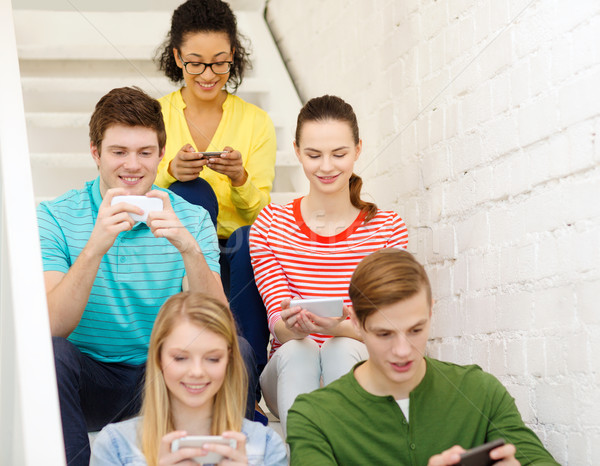 smiling students with smartphone texting at school Stock photo © dolgachov