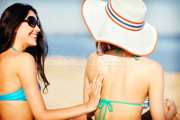 girls applying sun cream on the beach Stock photo © dolgachov