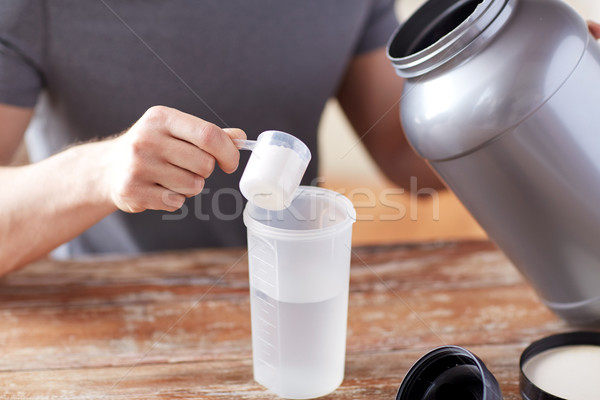close up of man with protein shake bottle and jar Stock photo © dolgachov