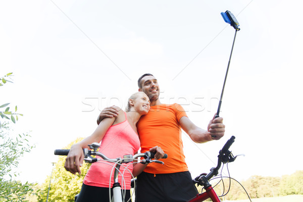 Stock photo: couple with bicycle and smartphone selfie stick
