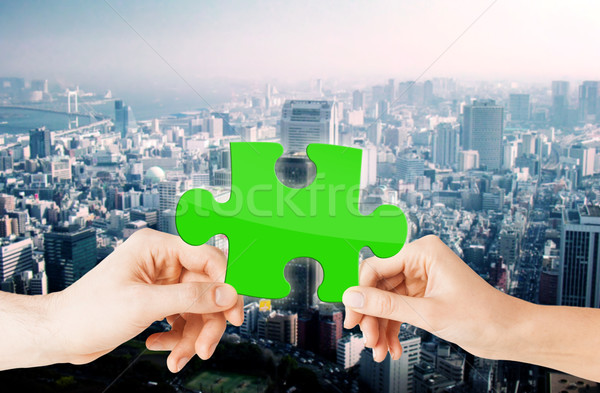 hands with green puzzle over city background Stock photo © dolgachov