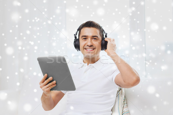 smiling man with tablet pc and headphones at home Stock photo © dolgachov