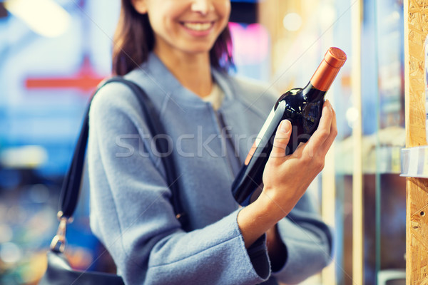 Stock photo: happy woman choosing and buying wine in market