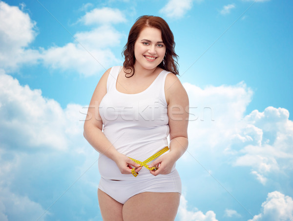 Stock photo: happy young plus size woman with measuring tape