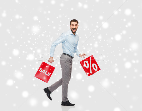 smiling man with red shopping bags over snow Stock photo © dolgachov