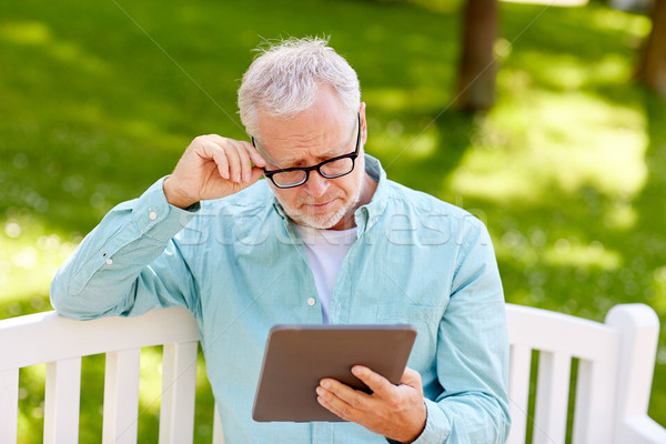 senior man with tablet pc at summer park Stock photo © dolgachov