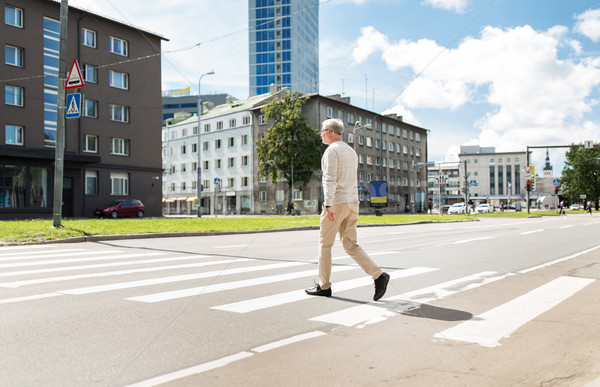 senior man walking along city crosswalk Stock photo © dolgachov