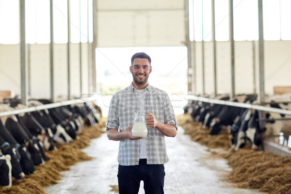 man or farmer with jug of cows milk on dairy farm Stock photo © dolgachov