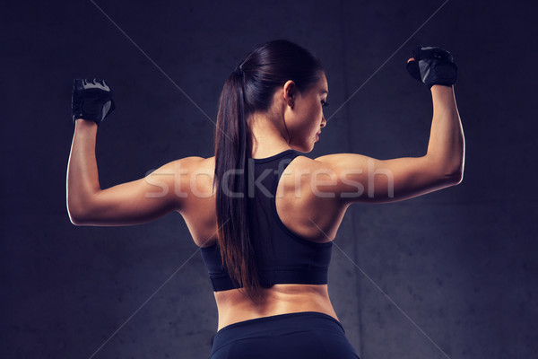 young woman flexing muscles in gym Stock photo © dolgachov