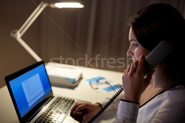 woman with laptop calling on phone at night office Stock photo © dolgachov