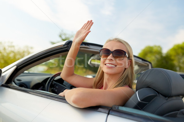happy young woman in convertible car waving hand Stock photo © dolgachov