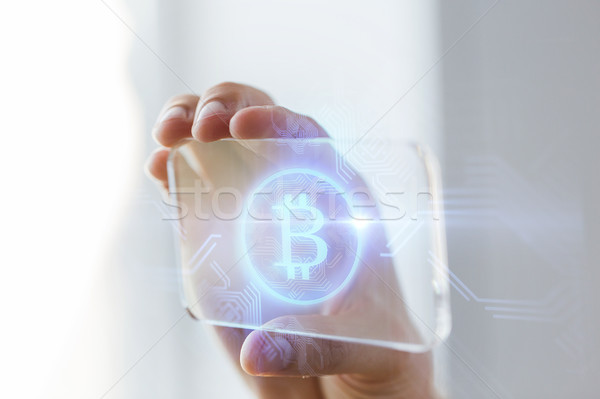 Stock photo: close up of bitcoin on transparent smartphone