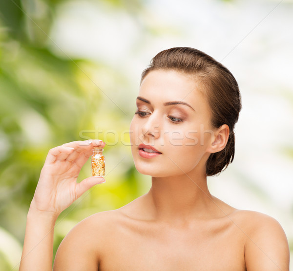 Stock photo: beautiful woman showing bottle with golden dust