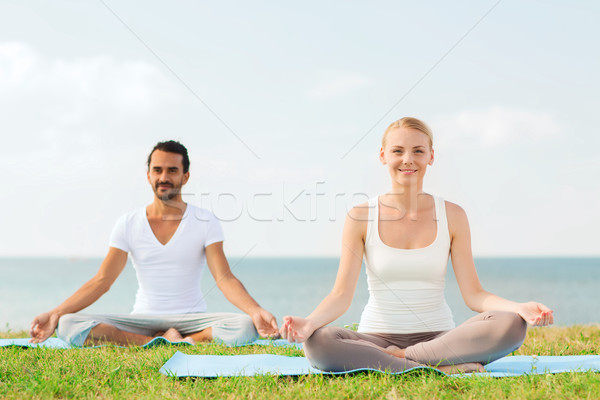 smiling couple making yoga exercises outdoors Stock photo © dolgachov