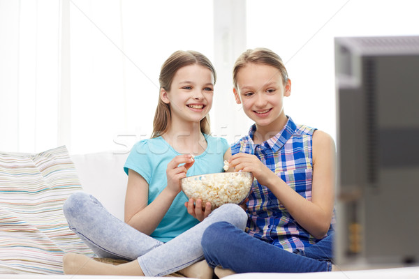 happy girls with popcorn watching tv at home Stock photo © dolgachov