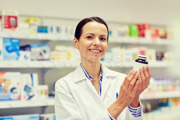 happy female pharmacist with drug jar at pharmacy Stock photo © dolgachov