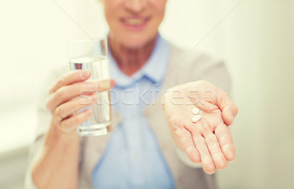 close up of senior woman with water and pills Stock photo © dolgachov