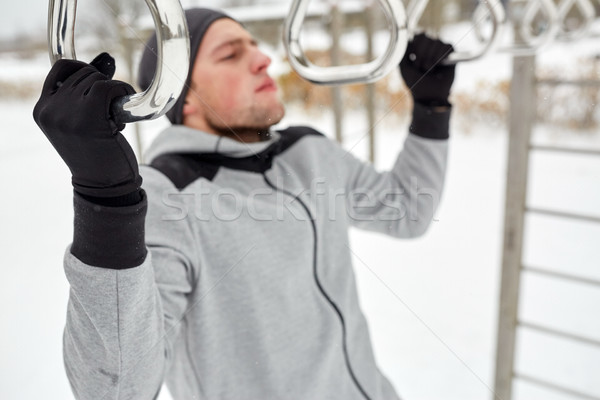 young man exercising on horizontal bar in winter Stock photo © dolgachov