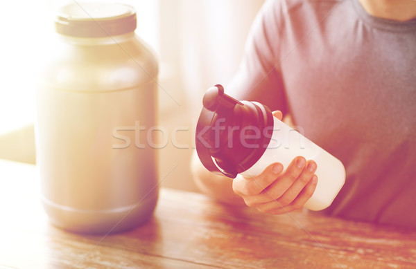 close up of man with protein shake bottle and jar Stock photo © dolgachov