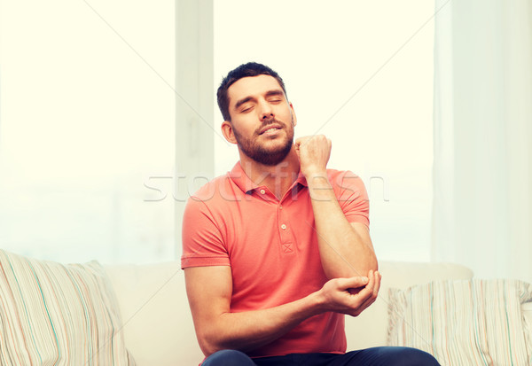 unhappy man suffering from pain in hand at home Stock photo © dolgachov