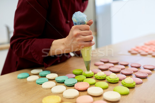 Stock photo: chef with injector squeezing filling to macarons